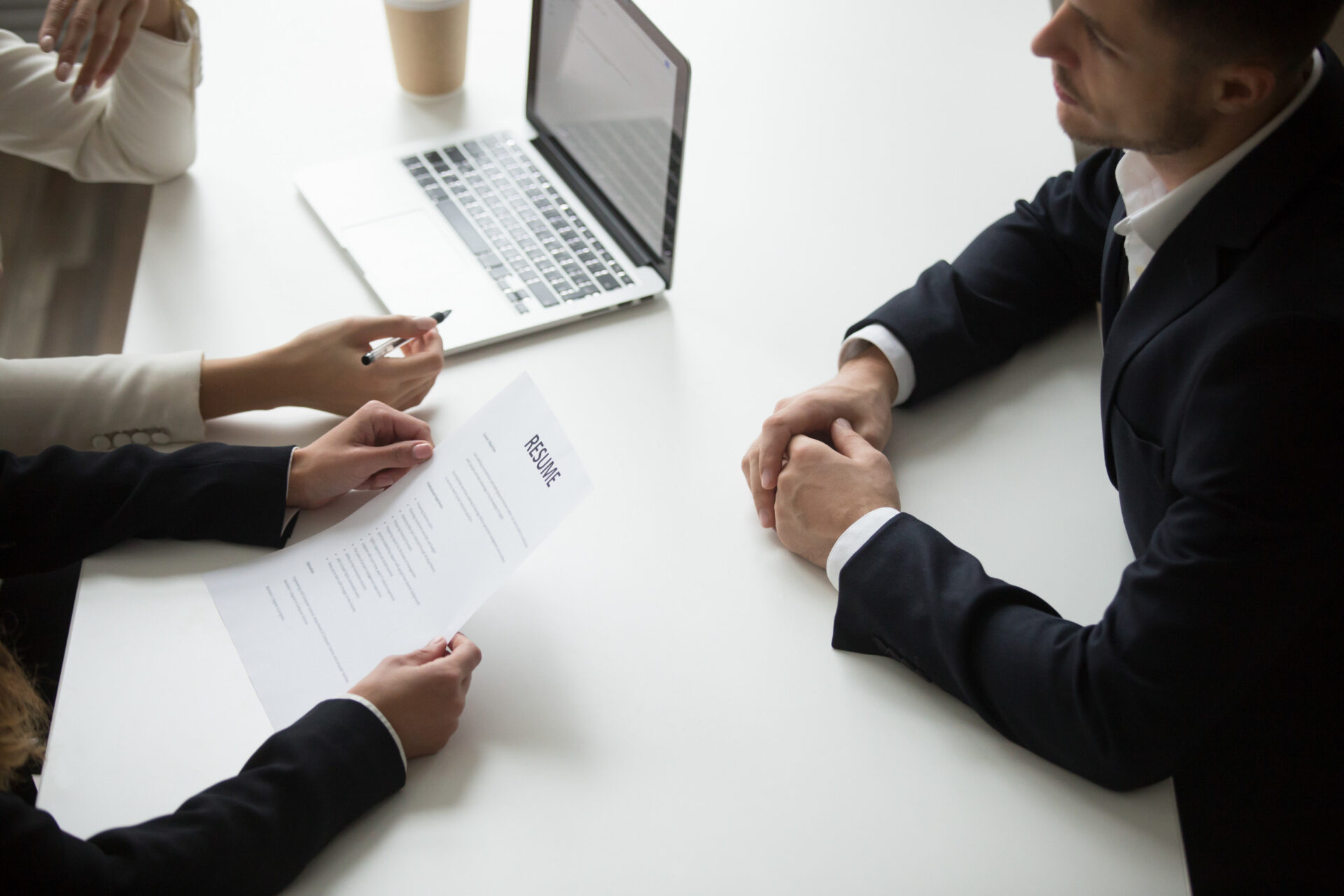 An image id three employees setting at the same meeting table with one laptop and it seems two of them are interviewing the third one