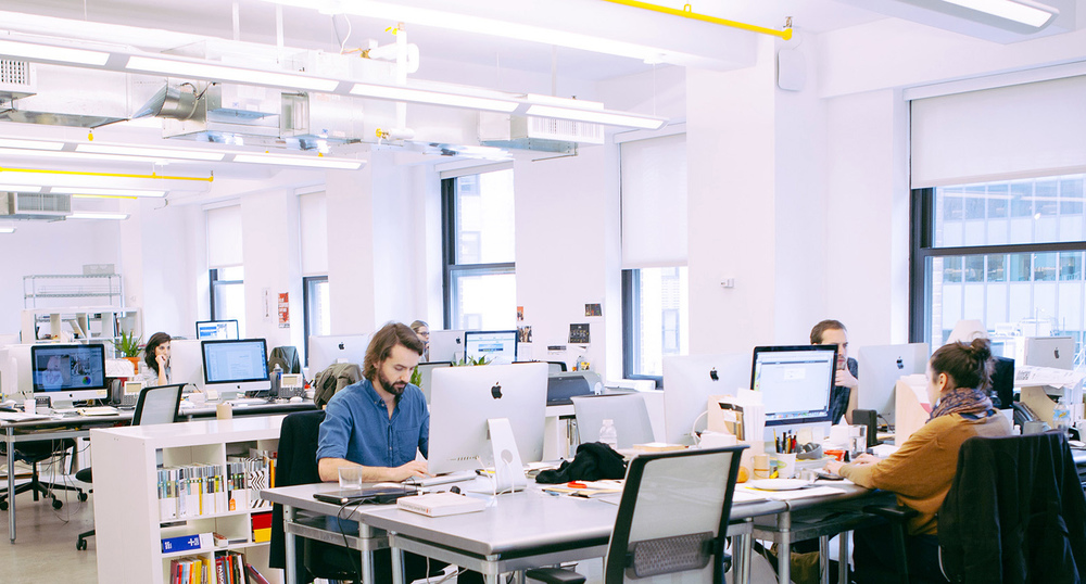 Several employees sitting at their desks in a modern office environment, focused on their computer screens. creating a scene of productive teamwork.