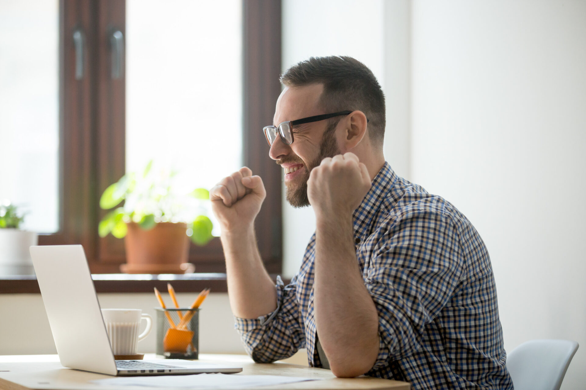 An employee setting on his laptop with a smile and a fest to explain that he is happy and satisfied.