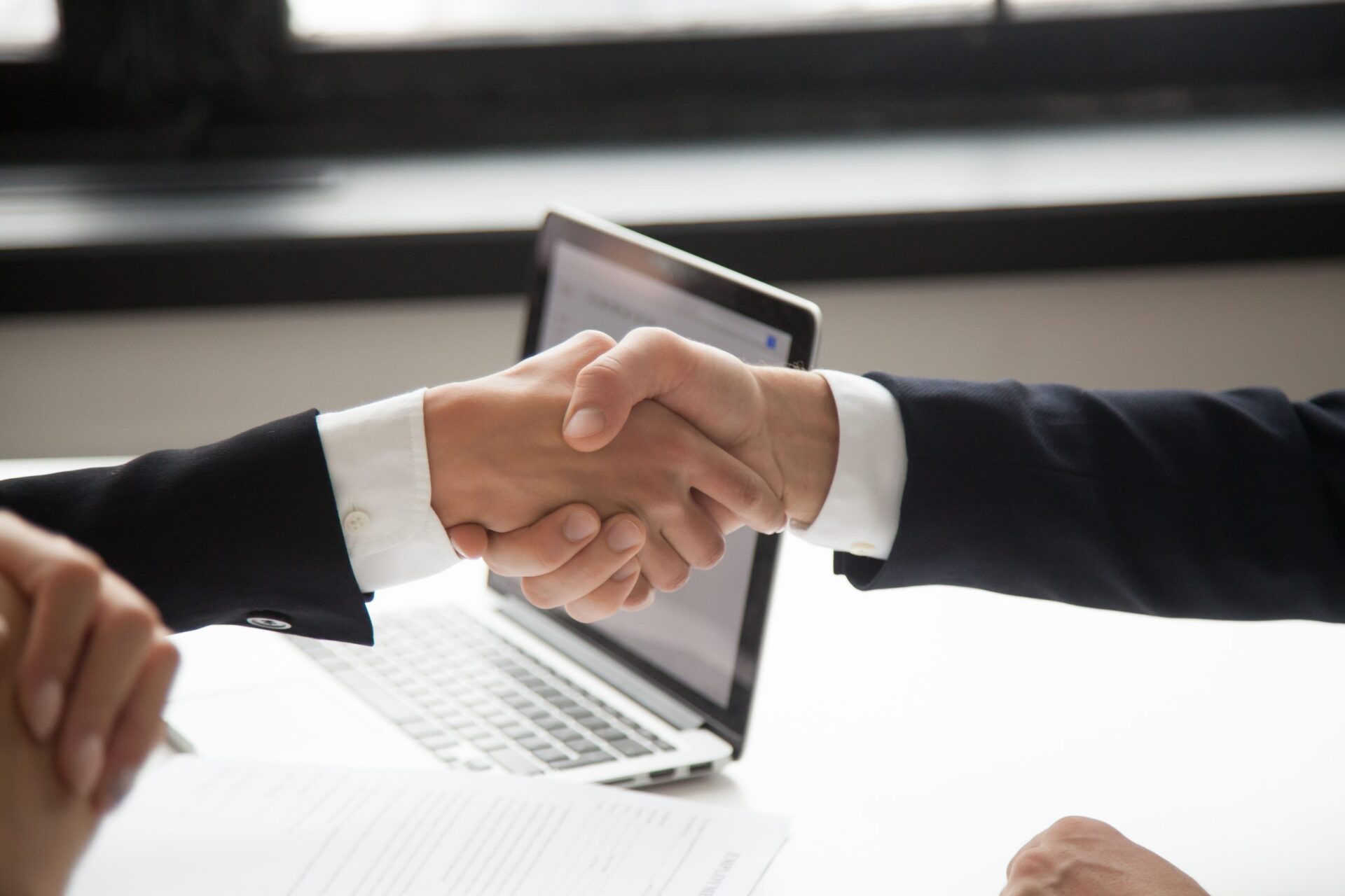Am image of two colleagues wearing suites shaking hands