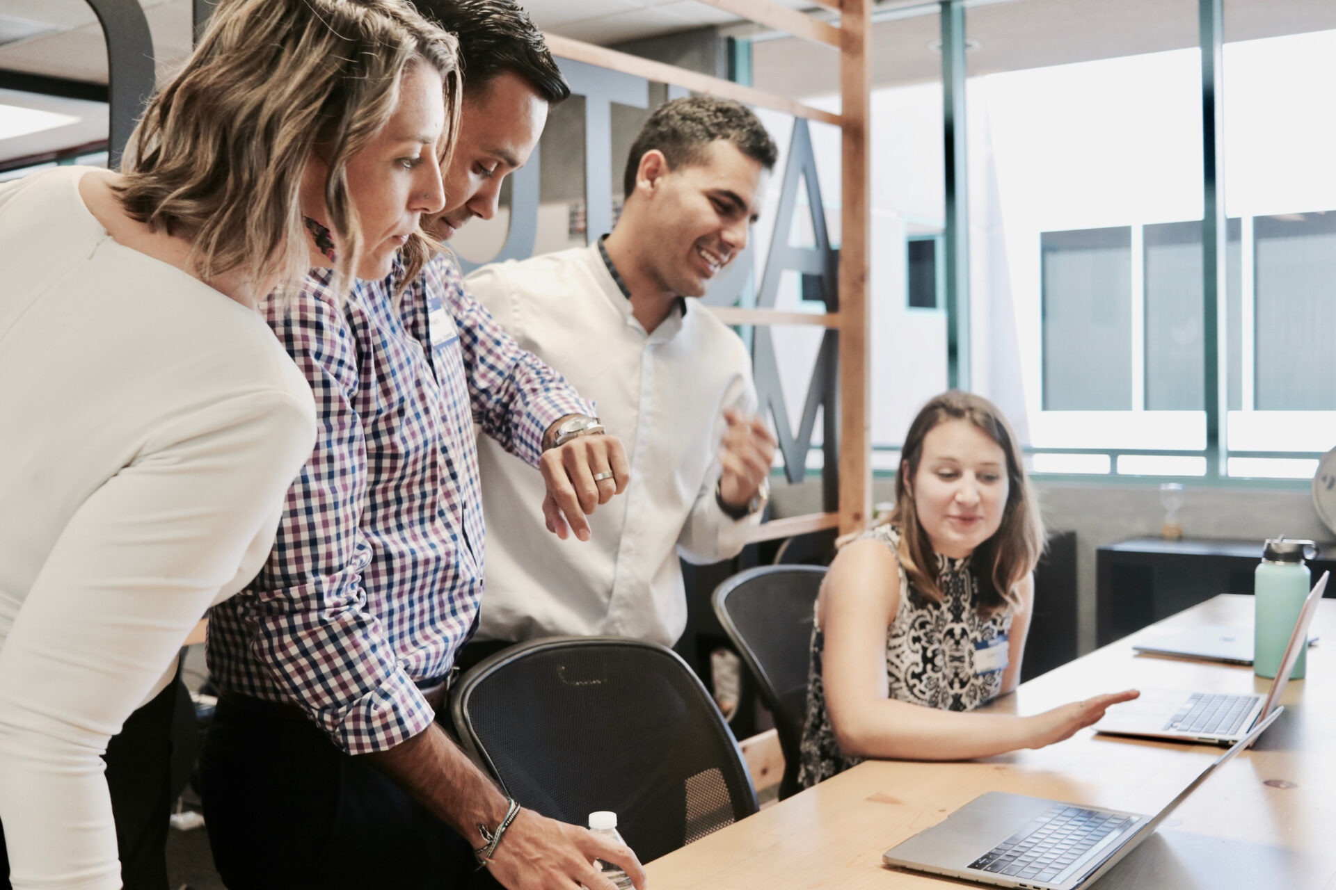 An image of four employees looking at the same laptop screen