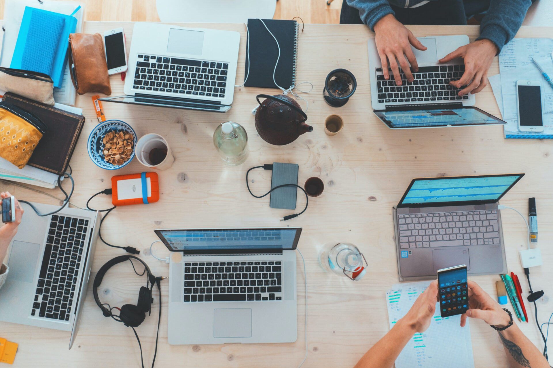 A top view of a meeting table with five laptops and different employees' belongings