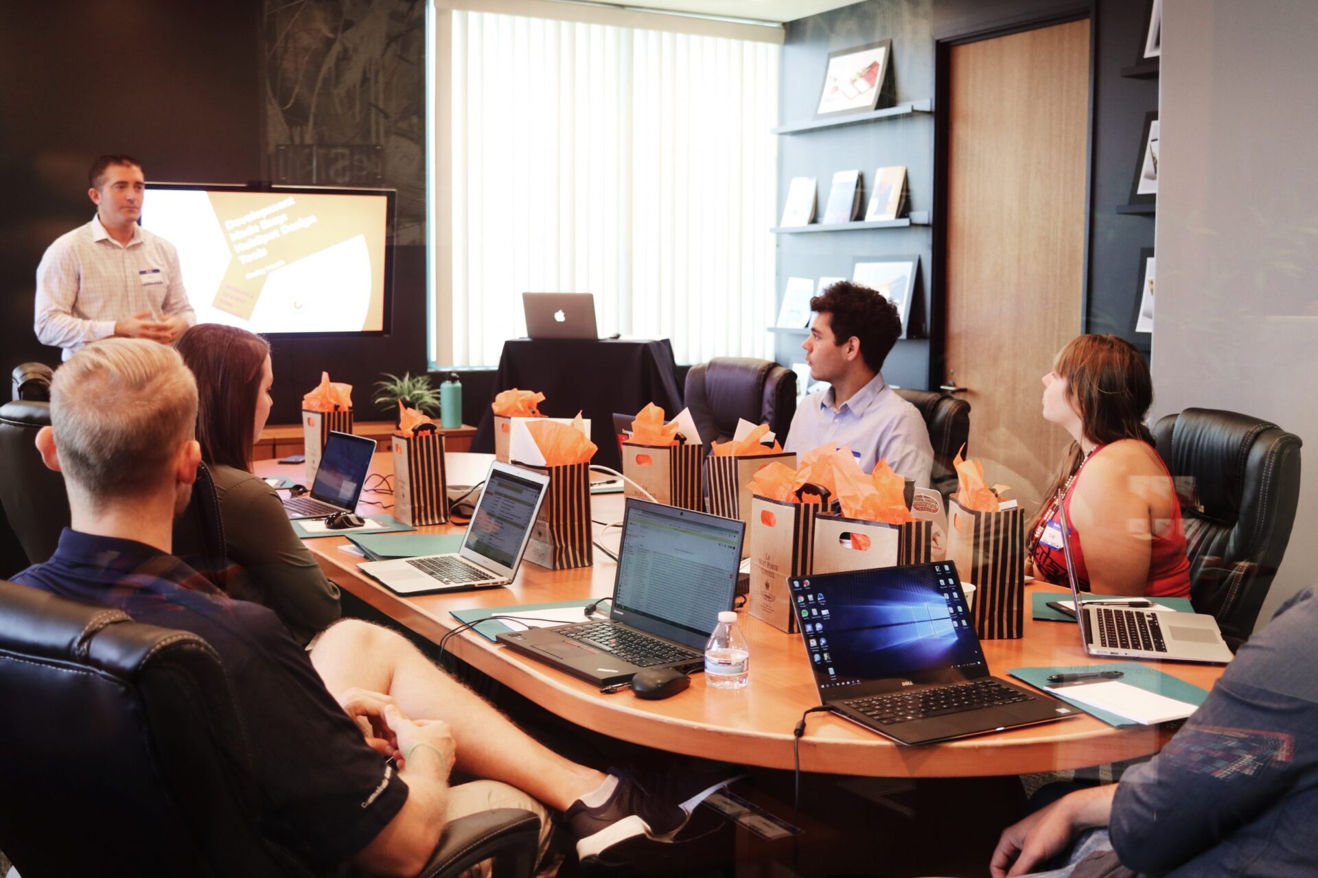 A group of professionals seated around a large conference table in a modern office, participating in a meeting or training session.