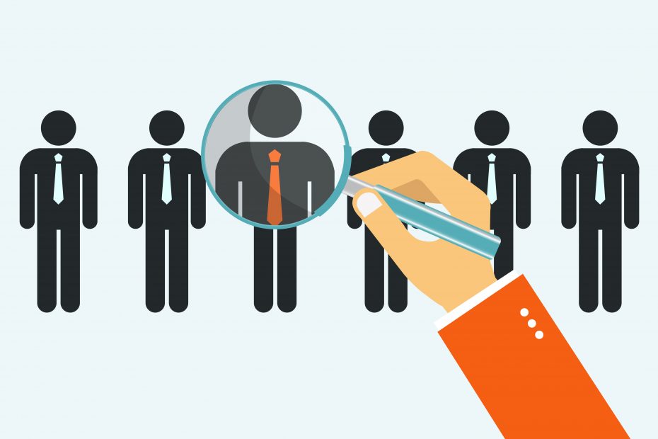 An illustration of a hand holding a magnifying glass over one of several identical figures wearing ties, highlighting that figure in detail.