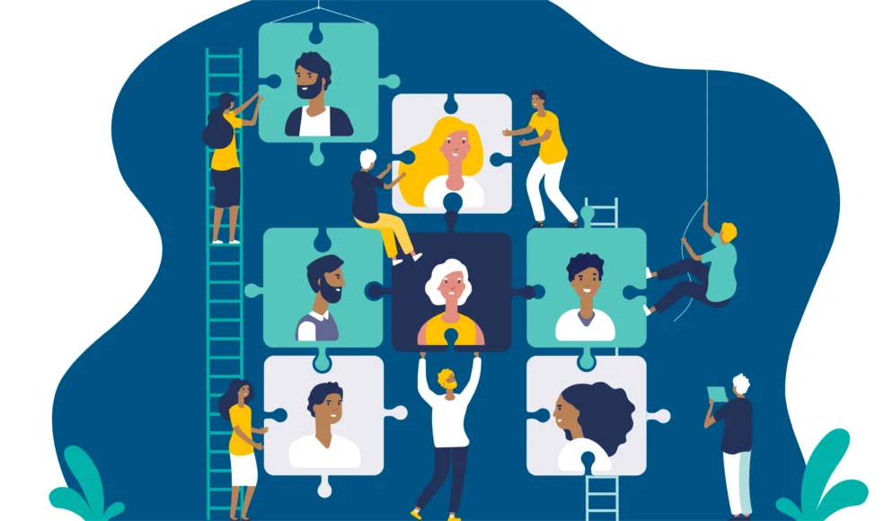 An illustration of diverse individuals working together to assemble a large puzzle, each piece featuring a different person’s portrait. The puzzle pieces are interconnected, symbolizing teamwork and collaboration. Some individuals are using ladders, ropes, and scaffolding to reach and place the puzzle pieces, while others are guiding and supporting from below. The background is dark blue with abstract shapes and green foliage at the bottom corners, adding a vibrant and dynamic feel to the scene. The overall theme emphasizes unity, diversity, and the collective effort required to achieve a common goal.