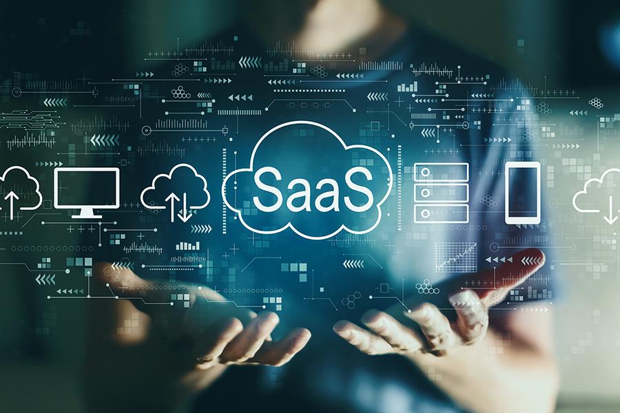 A photograph of a person holding their hands out, with various digital icons and graphics superimposed over them. The central focus is on a cloud icon with the word "SaaS" (Software as a Service) inside it. Surrounding this are icons representing different aspects of technology and cloud computing, such as a computer, cloud storage, server, and smartphone. The background is blurred, drawing attention to the floating digital elements and the person's hands, which are illuminated by the glow of the graphics. The overall theme is technology, innovation, and cloud-based software solutions.