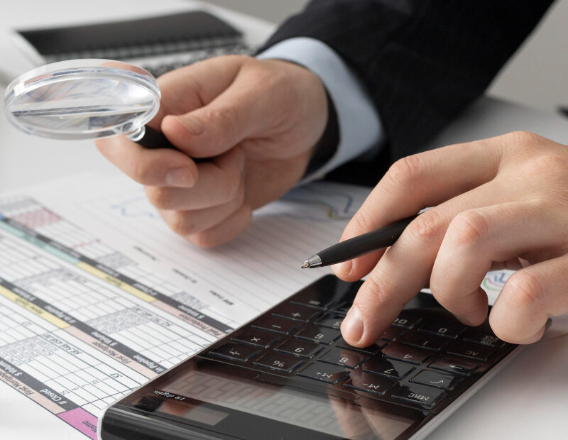 An image that shows a businessman calculating finance numbers using calculator.