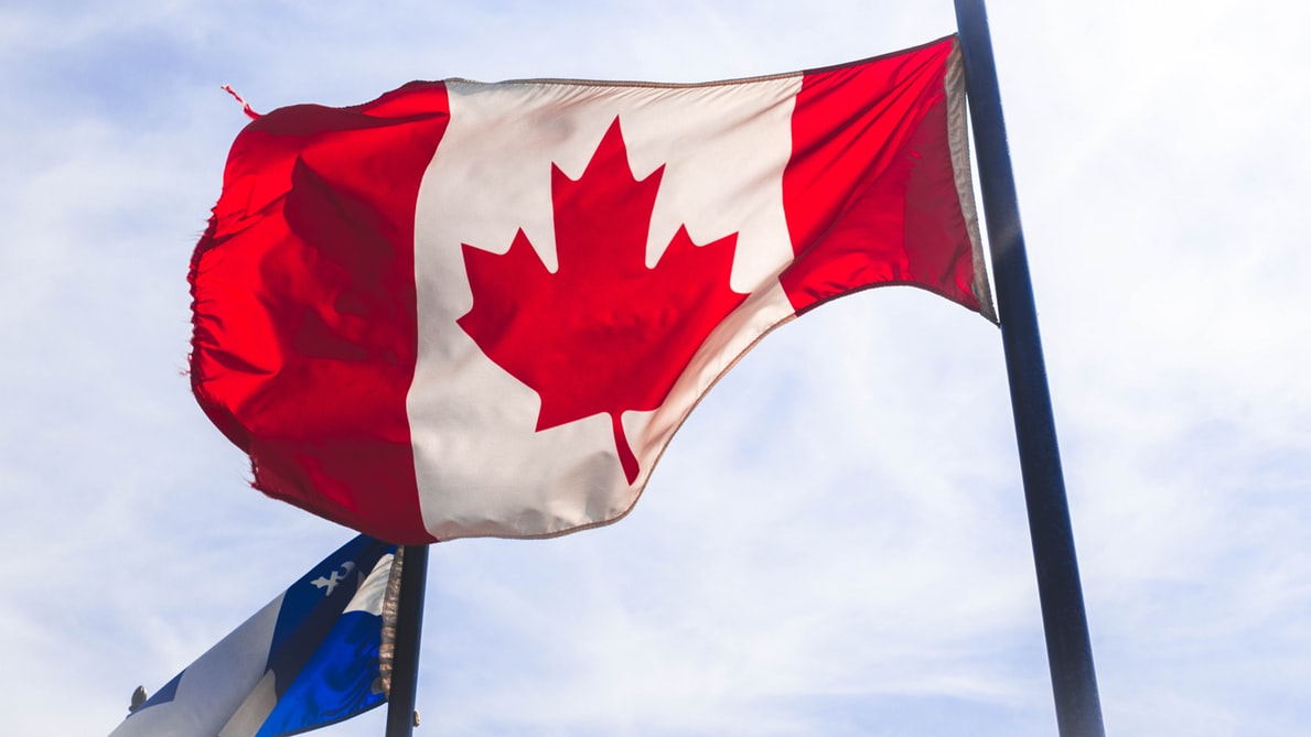An image of Canada flag waving in the blue sky