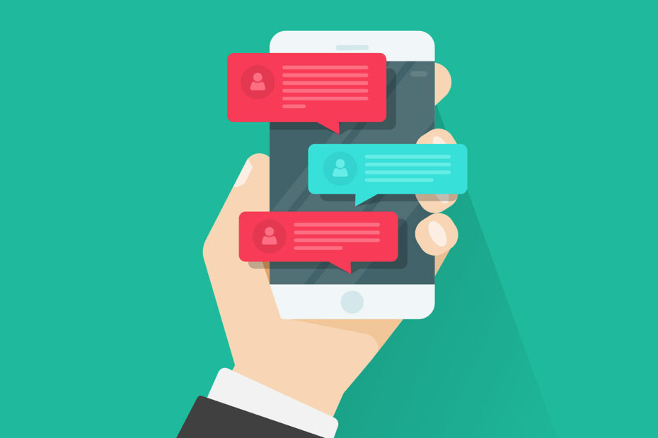 An illustration of a hand holding a smartphone with several chat bubbles displayed on the screen. The chat bubbles are in red and blue, indicating a conversation. Each bubble contains text and a small user icon, suggesting a messaging app. The background is a solid teal color, providing a clean and simple backdrop for the focus on the phone and chat bubbles. The hand is dressed in a suit sleeve, indicating a professional context.