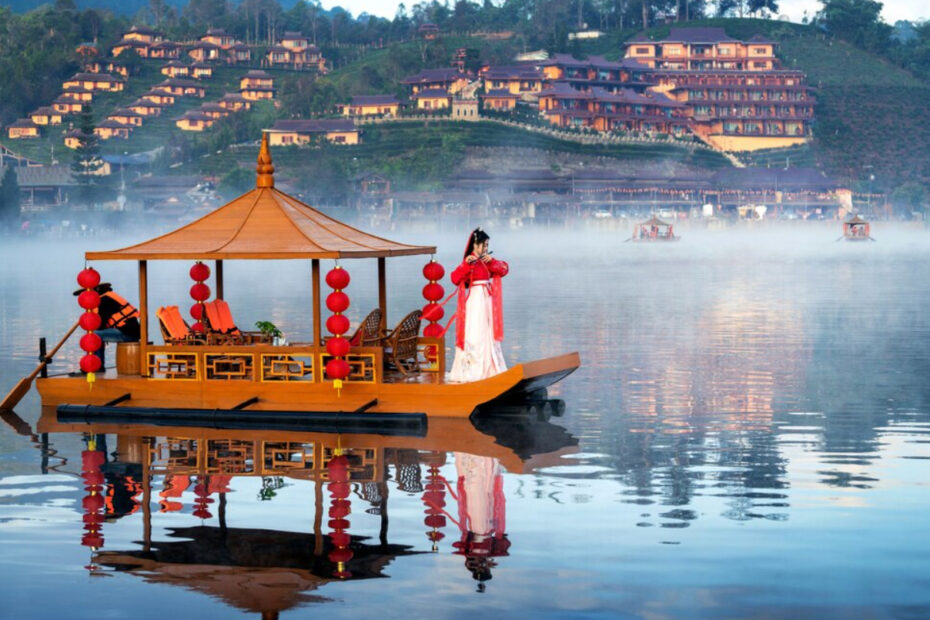 An image of a Chinese style boat and women wearing a Chinese outfit in the middle of the water