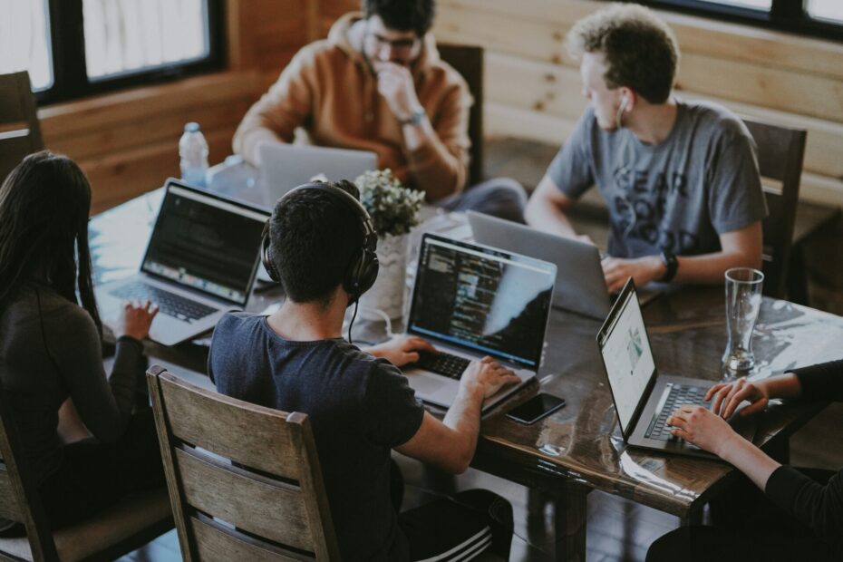 An image of number of employee working on the same table each is looking at his laptop