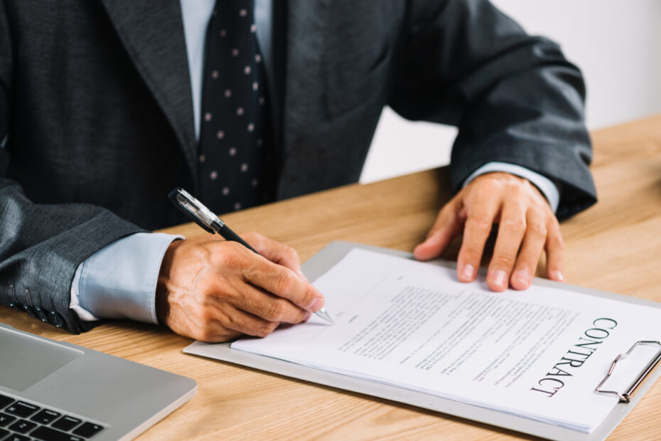 An image of an employee sitting on a wooden disk signing a work contract