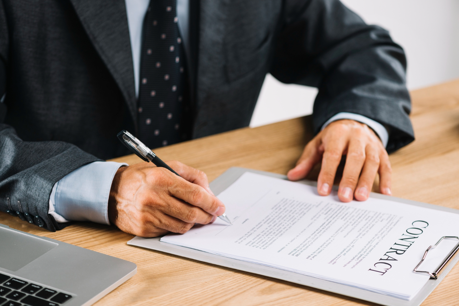 An image of an employee sitting on a wooden disk signing a work contract