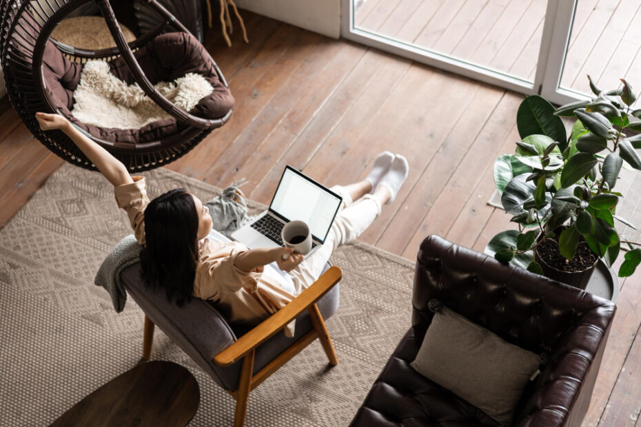 An image of a female women working from home, while drinking coffee in front of her laptop in the daylight