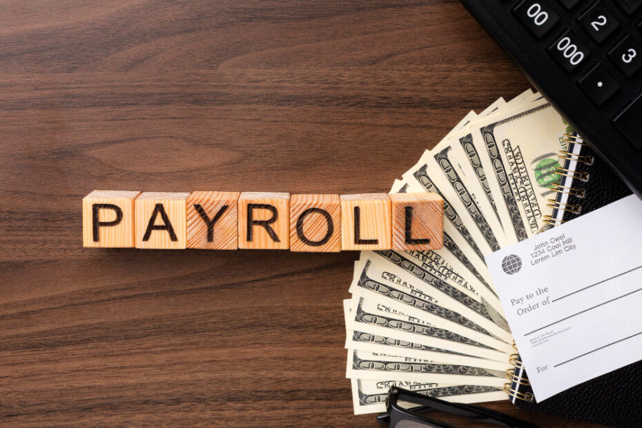 an image of the word pay roll written on wooden boxes and some cash near it in a wooden disk