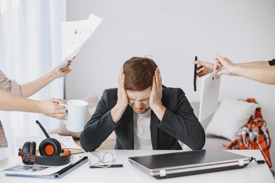 Stressed marketing professional experiencing burnout at work surrounded by overwhelming tasks and demands — representing creative team burnout.